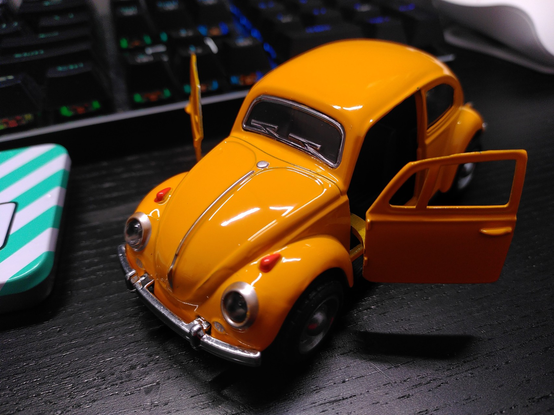 gelboranger VW Käfer, mit offenen Türen auf einem Schreibtisch