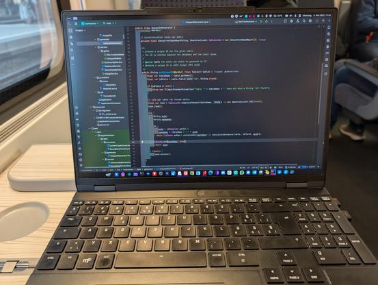 A photo of a laptop in a train showing an IDE with some Java code.