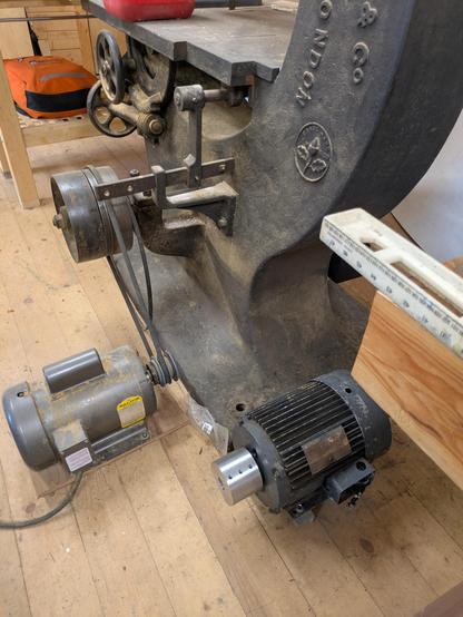 A new flat belt pulley on an old motor near a much older 30" bandsaw.