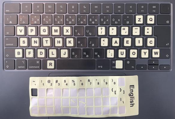 Photo looking down on a black Apple MacBook Japanese keyboard, with 34 luminous yellow stickers defining a split layout with R (backspace, shift) and space on thumbs, and home keys SNTH, AEIC (a variant of the inverted Hands Down Promethium layout).

The rest of an Apple USA English keyboard layout sticker sheet is lying on the trackpad, the number row and a few more punctuation keys