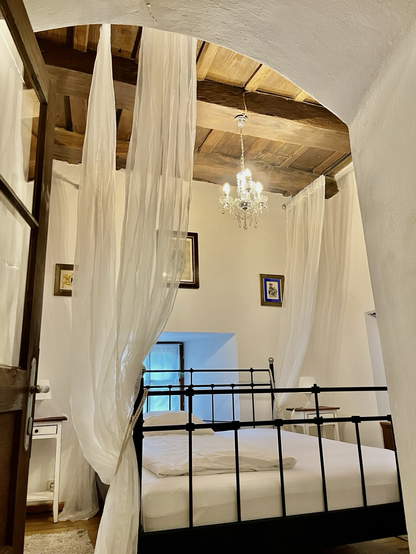 Innenansicht von meinem Zimmer im Torwächterhäuschen mit Vorhängen ums Bett und einer Holzdecke