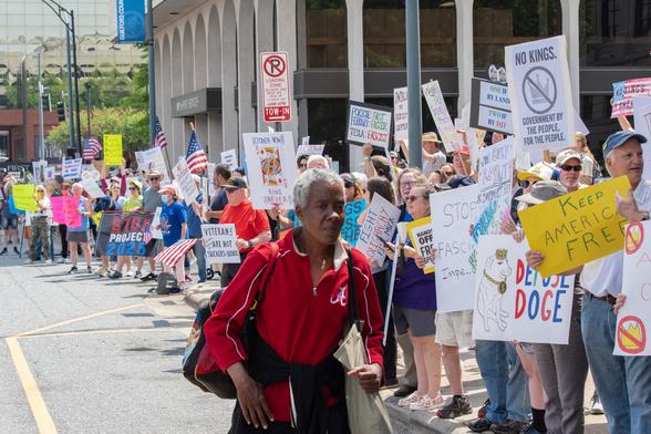 A woman walking in front of a line of picketers at the "Hands Off" protests from a few weeks ago.