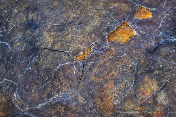 Close-up photo of a rock surface with thin white lines that resemble lightning