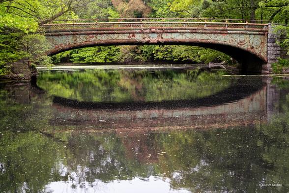 Photograph of an old iron bridge dated 1889 spanning the Lullwater near the Prospect Park Boathouse.