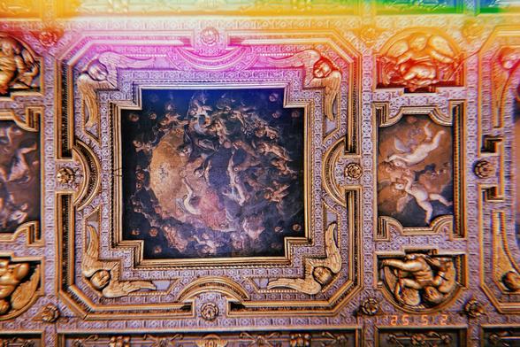 A luxuriously looking ceiling with opulent paintings and gold.