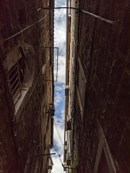 Looking up to the blue sky between the narrow alleyways of Split historic old town