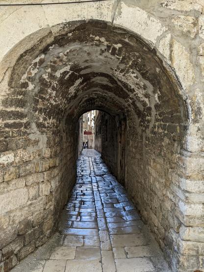 Split old town narrow historic walkway with the marble stone floor looking like polished after thousand years of pedestrians