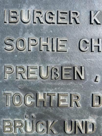 Eine Bronzetafel mit Inschrift. Im Wort Preußen mag das kleine SZ nicht so recht zwischen die Großbuchstaben passen.