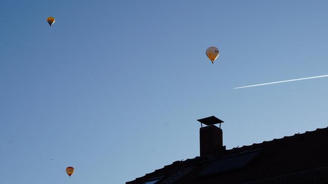 3 Ballons und Kondensstreifen über Dach