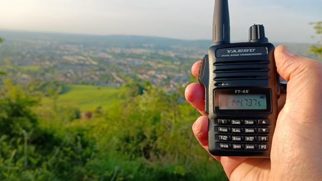In the foreground is my hand holding a Yaesu FT-4X hand held radio.
In the background is Cheltenham and further in the distance are The Malvern Hills.