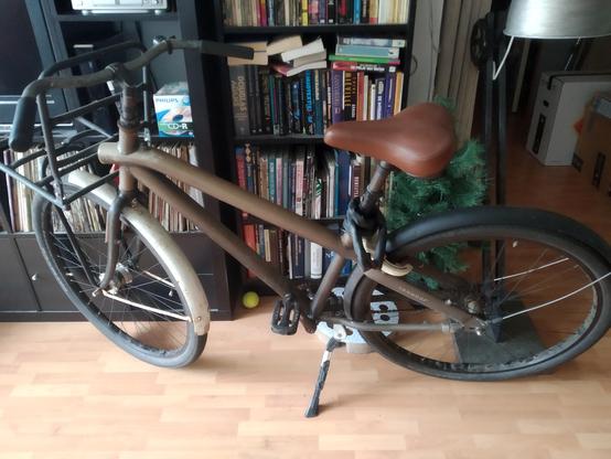 One VanMoof bike made complete from two. Ready to go. In front of a book case