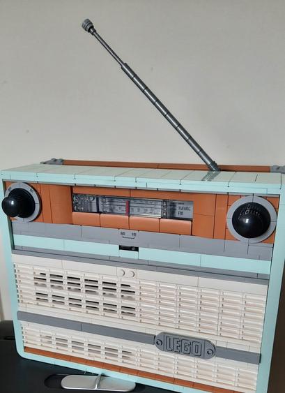 Replica of a 70's style AM/FM radio built from a Lego kit. Features include an antenna, a knob for volume and a dial displaying the radio channels.