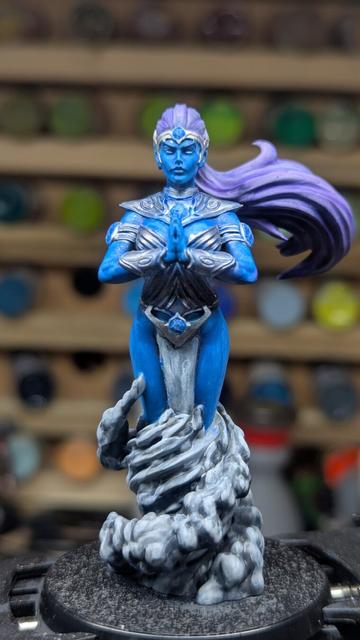 Blue female djinn with purple hair with smoke twirling around the figure