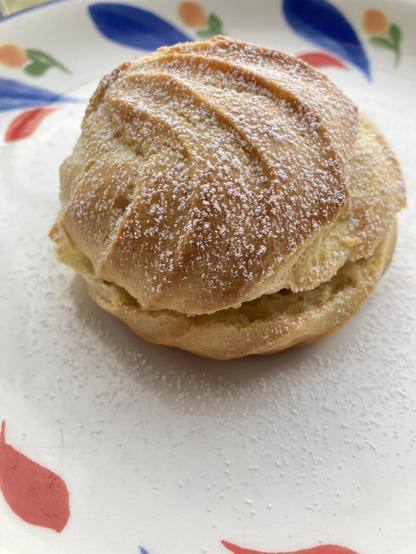 A cream puff filled with custard and dusted with powdered sugar.