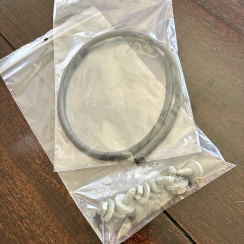 Two plastic bags, one containing a length of black vacuum hose sitting on top of the other containing six bolts.