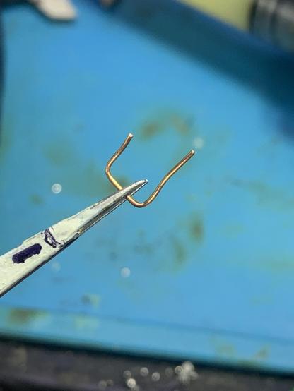 A piece of wire bent to fit two units of a 0.1 inch pitch prototyping board