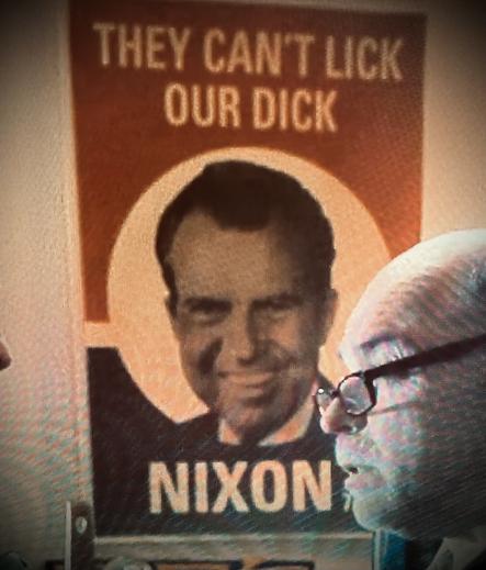 Grainy photo of an old poster hanging on a wall. It’s a photo of Nixon smiling with his name written below it. At the top is a slogan that reads “you can’t lick our dick.”