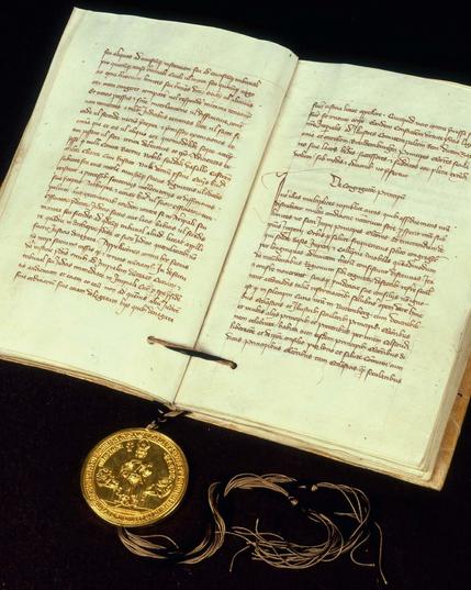 Das Trierer Exemplar der Goldenen Bulle Kaiser Karls IV., 10. Januar 1356. Aufgeschlagen. Das am Libell hängende goldene Siegel zeigt den thronenden Kaiser mit Zepter und Reichsapfel auf der Vorderseite (Avers) und eine stark stilisierte Ansicht der Stadt Rom auf der Rückseite (Revers). LABW, HStAS H 51 U 589.