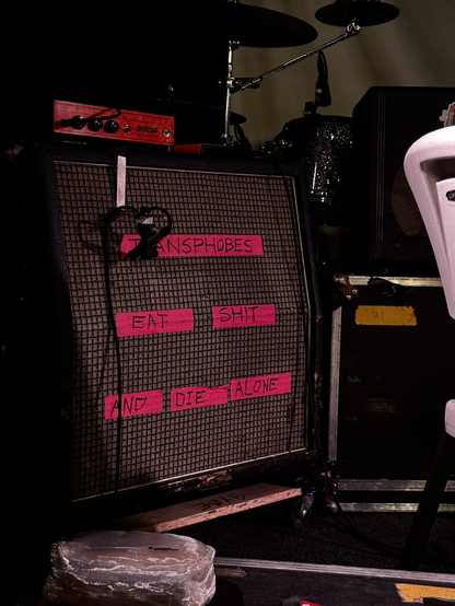 Sound equipment with red tape that says “transphobes eat shit and die alone”