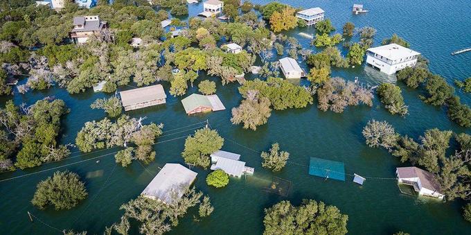 Aerial views of heavy flooding in Texas back in 2021 - entire homes are underwater with roofs just visible through the water.