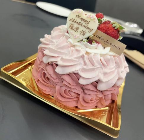 A pink rose-patterned cake with a “Happy Birthday” message and strawberries on top.
