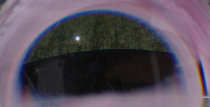 The deep black ridge and greenish-black surface of a black piece of glass are visible in the supposedly inner sphere. The outer sphere has undergone a point reflection, reflecting incoming light rays to create the illusion of a second sphere. This, in turn, undergoes a point reflection, so this image is perspectively correct. In addition, it is enlarged.