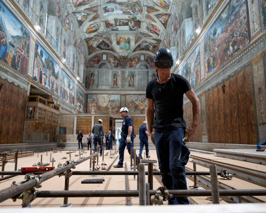 Photo from the Guardian website, captioned: 'Workers set up scaffolding to install the chimney in the Sistine Chapel for the conclave.'

In the photo several workers in hard hats are beginning to put together scaffolding on the floor of the Sistine Chapel, with Michelangelo's famous ceiling visible overhead.

Photograph: Vatican Media/Reuters - Guardian link: https://www.theguardian.com/world/2025/may/07/cardinals-begin-choosing-new-pope-conclave