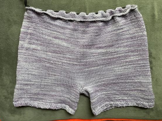 knitted purple shorts back view on grey cushion
