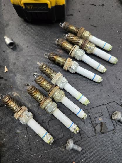 A set of used spark plugs. Dirty and worn sitting on a table.