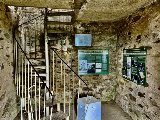 Innenansicht vom Turm mit einem im Boden einbetonierten Grenzstein zu Ungarn, Schautafeln und einer Wendeltreppe