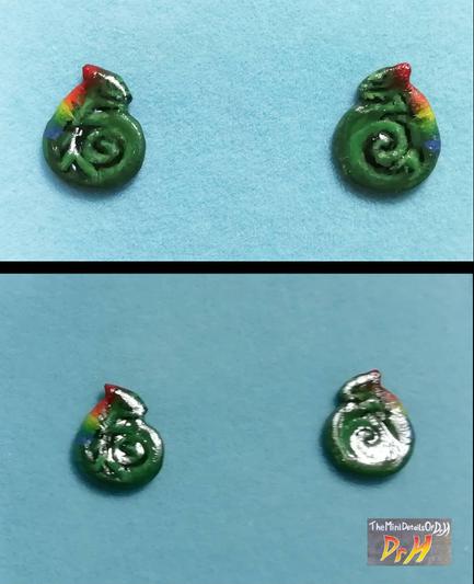 Pair of Chameleon earrings. Chameleon is curled up and has a rainbow down it's back. Lit to show the glossy finish.