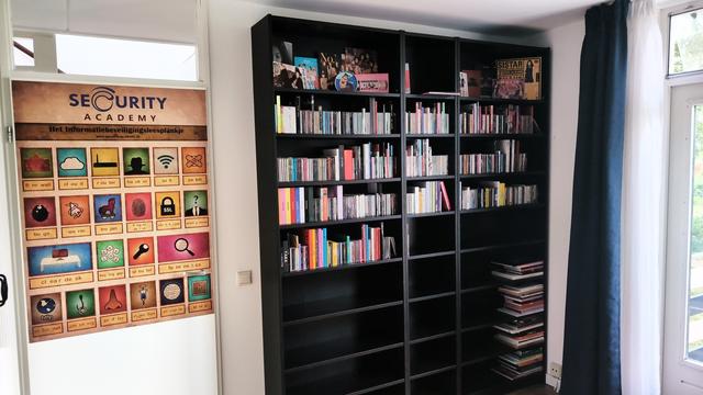 The other side of the room sporting a big wall-filling bookcase half full of CDs (with the rest empty for future CDs) that'll fall on the background of conference calls, and a big poster on the door from Security Academy in the Netherlands that shows security related words with pictures in the way used to teach reading in primary school.