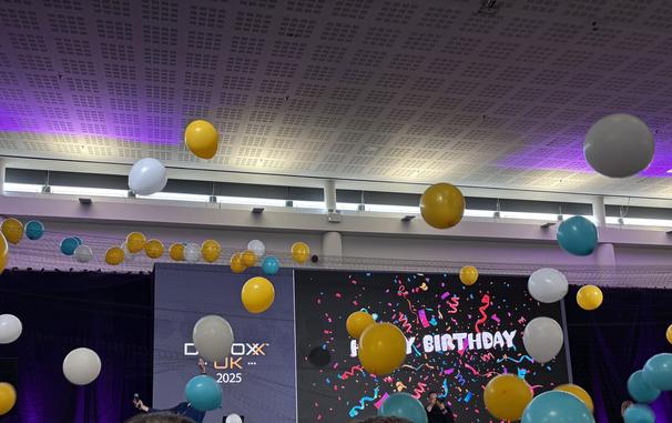 A Happy Birthday sign with gold, blue and white balloons dropping to the ground.