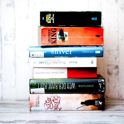 pile of books including Stephen King "It", Patrick Rothfuss, Maggie Stiefvater and more. Text: Verbotene Fantasybücher