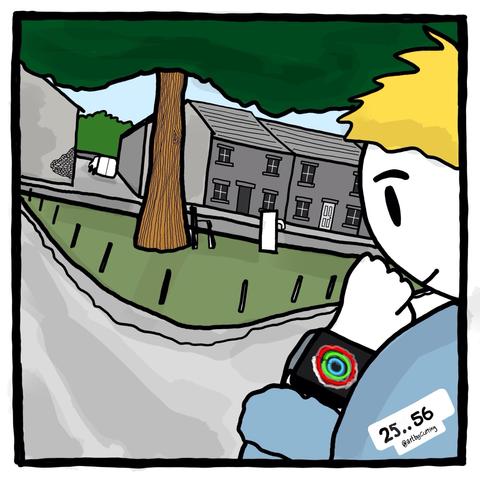 Pictured looking at my Apple Watch with completed rings animation. In front of village green, oak tree, fountain and terraced houses. All under a cloudless blue sky.