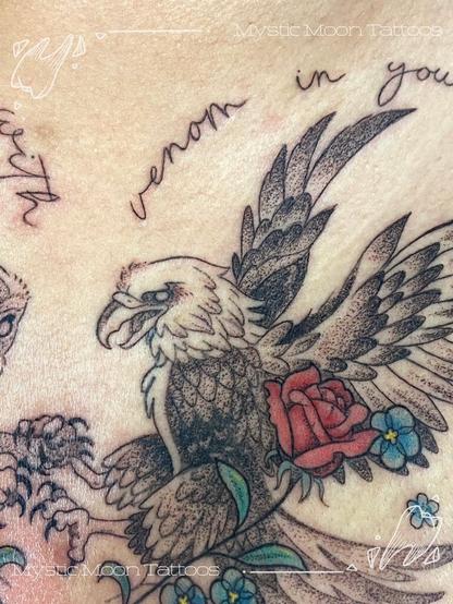 A chest tattoo depicting an owl and an eagle with locked talons, holding flowers, with script reading "You were not born with venom in your veins, it was put there"