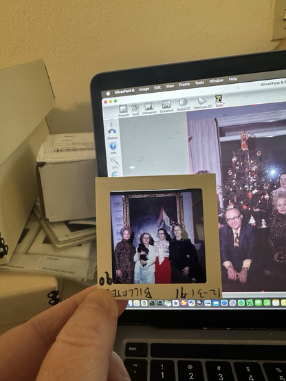 A medium format square slide held up against a laptop screen with the scanned image of the penultimate slide. Both are from New Years Eve 1972.