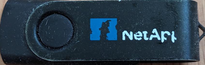 A Black USB thumb drive with a blue logo and the words "NetApp" written in white printed on the side.