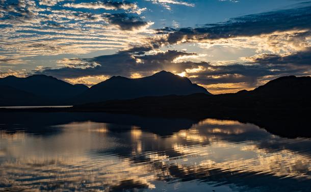 Lots of different clouds reflected in rippling water.