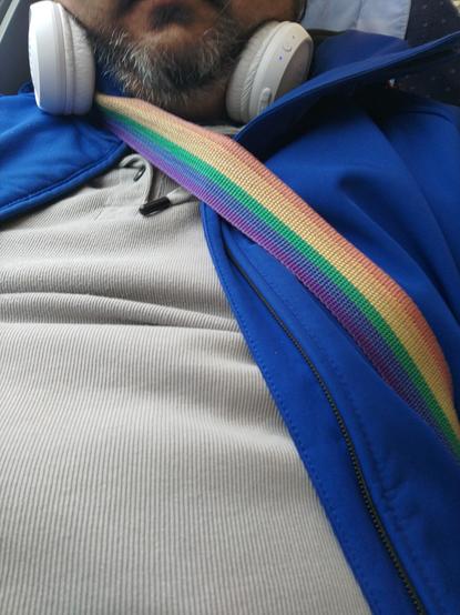 Regenbogenband über blauer Jacke und grauem Hoodie