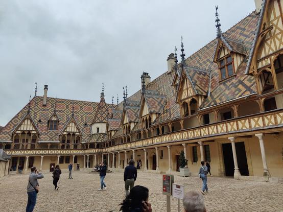 Vue sur la cours des Hospices de Beaune avec ses toits en tuiles vernissées aux arrangements géométriques dans les tons jaune, ocre, vert et noir.