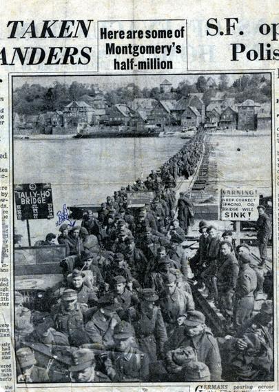 A newspaper clipping of hundreds of German soldiers crossing a bridge under the watch of British soldiers. Bob Hearn has been tagged in pen.