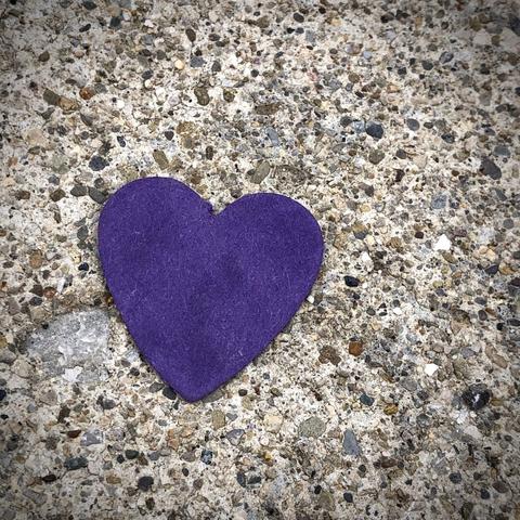 A Purple Heart maybe made of felt rests on concrete
