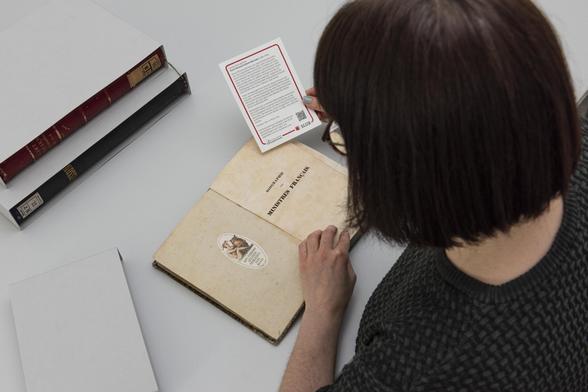 Eine Mitarbeiterin der SLUB beim Einlegen einen Hinweises in die Bücher.
