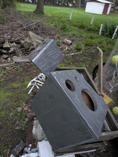 The two silver speaker enclosures (see photo 4 alt-text), with no speakers, are hanging in the air for the silver paint to dry. My neighbor's green yard with a little white shed is visible.