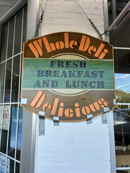 Whole deli sign held up by a chain and repositioned with duct tape