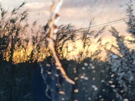 Tramonto visto attraverso la pioggia sul parabrezza dell'auto