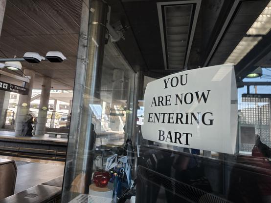 Millbrae BART entrance with a sign in all caps, bold, sans swift, reading "YOU ARE NOW ENTERING BART"