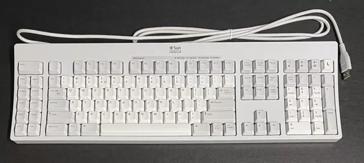 Photograph of a Sun type 7 keyboard, in the US UNIX layout. It has a real Compose key which lets me type things like 🤷 and ℵ₀ (those are Compose-s-h-r-u-g and Compose-a-l-e-p-h Compose-0-v in my custom mapping), and eleven extra keys on the left labelled Help, Stop, Again, Props, Undo, Front, Copy, Open, Paste, Find, and Cut. I don't use those. The keyboard feels lovely to type on.
