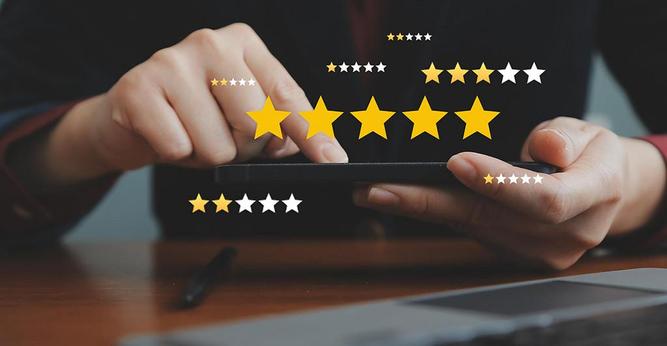 Auf dem Foto sind die Hände einer Person zu sehen, die ein Tablet hält. Drumherum sind Sterne von Bewertungen eingeblendet. Das Foto stammt von AdobeStock.
